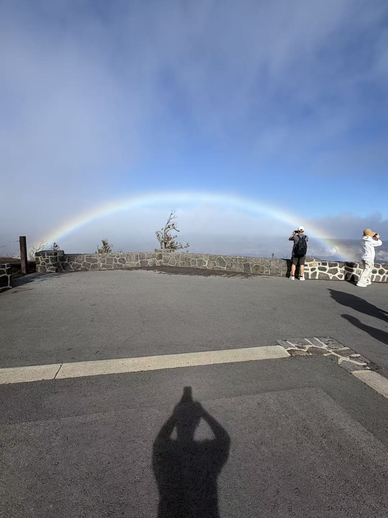 Guests at a volcanic overlook beneath a rainbow